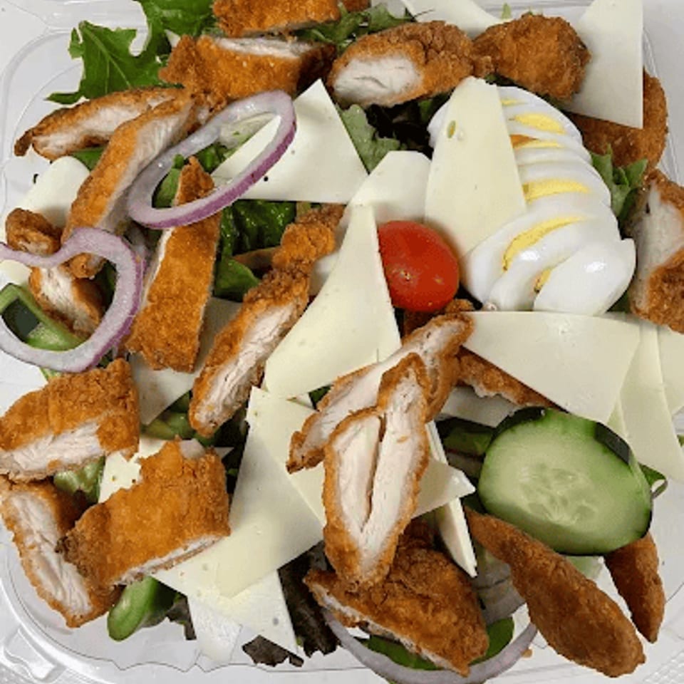Crispy chicken cutlets, cheese, red onion, tomato, cucumber, and hard-boiled egg on a bed of greens.